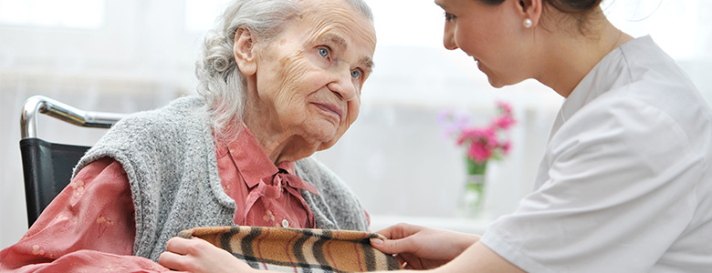 vårdpersonal som lägger en filt över äldre kvinna