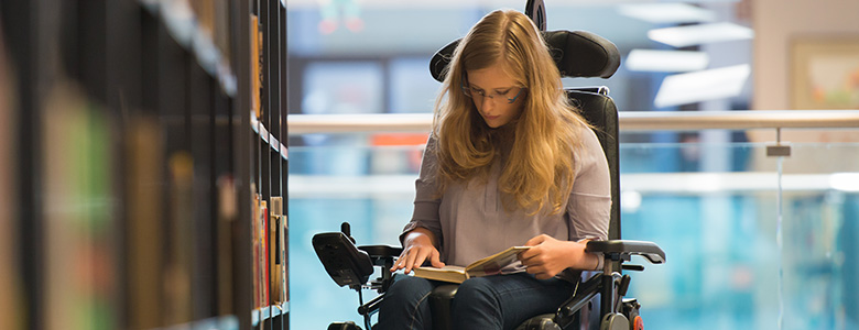 kvinna i rullstol som läser en bok