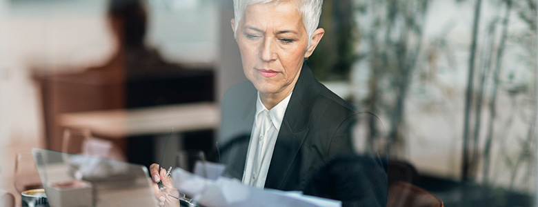 kvinna på kontor som läser en bunt med papper